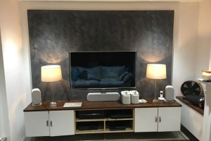Modern living room with a sleek TV setup, wooden furniture, ambient lighting, and contemporary décor elements